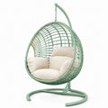 Sillón colgante de ratán sintético verde con cojines crema y estructura de acero